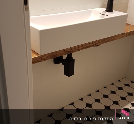 כיור עם ברז שחור וצנרת מתחת